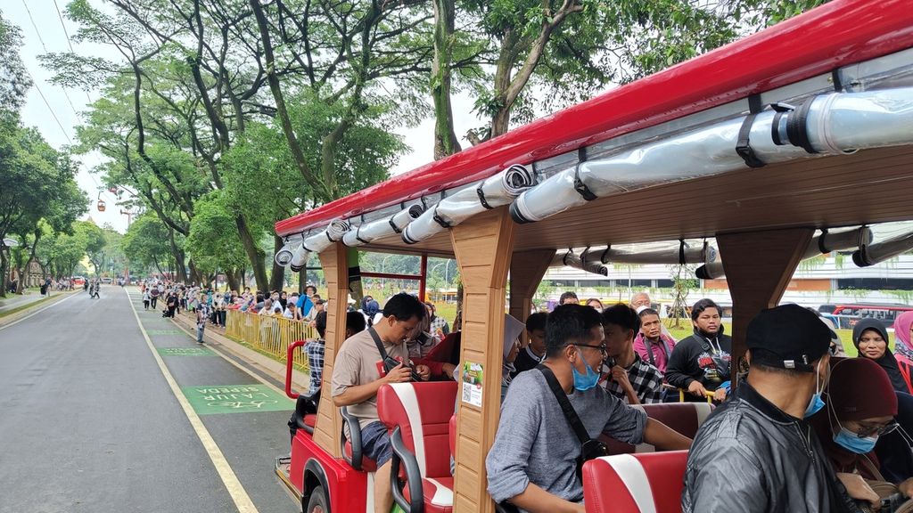 Ratusan pengunjung Taman Mini Indonesia Indah (TMII) yang sedang mengantre bus antar-jemput listrik di Kawasan TMII, Jakarta Timur, Senin (26/12/2022). Keterbatasan jumlah bus listrik yang tersedia memicu antrean panjang pengunjung yang ingin mencobanya.