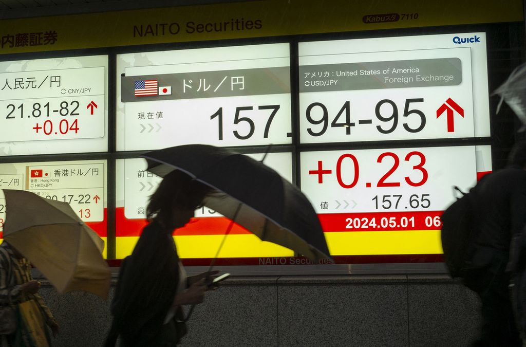 Pedestrians cross in front of an electronic board displaying the exchange rate of the yen against the US dollar in Tokyo, Japan, on May 1, 2024.