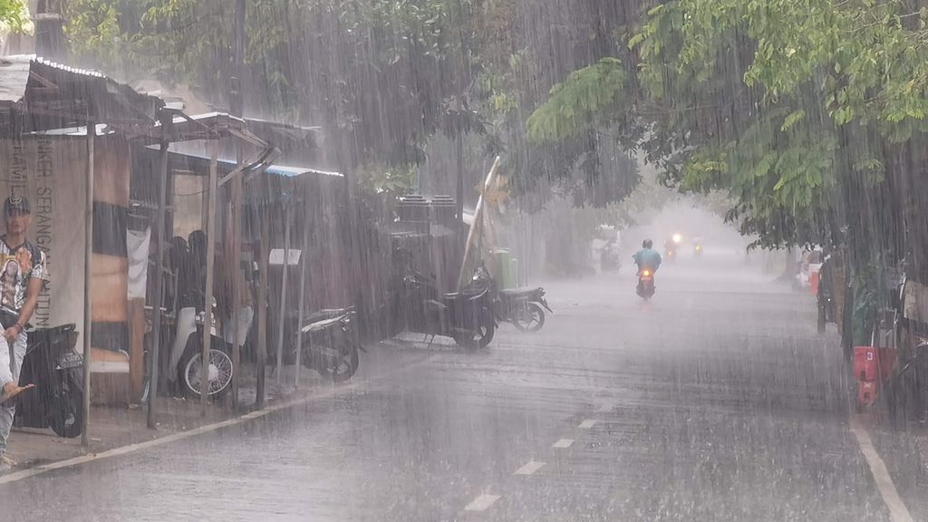 Pengguna jalan melintas saat hujan deras melanda Kota Mataram, Nusa Tenggara Barat, Februari 2021.