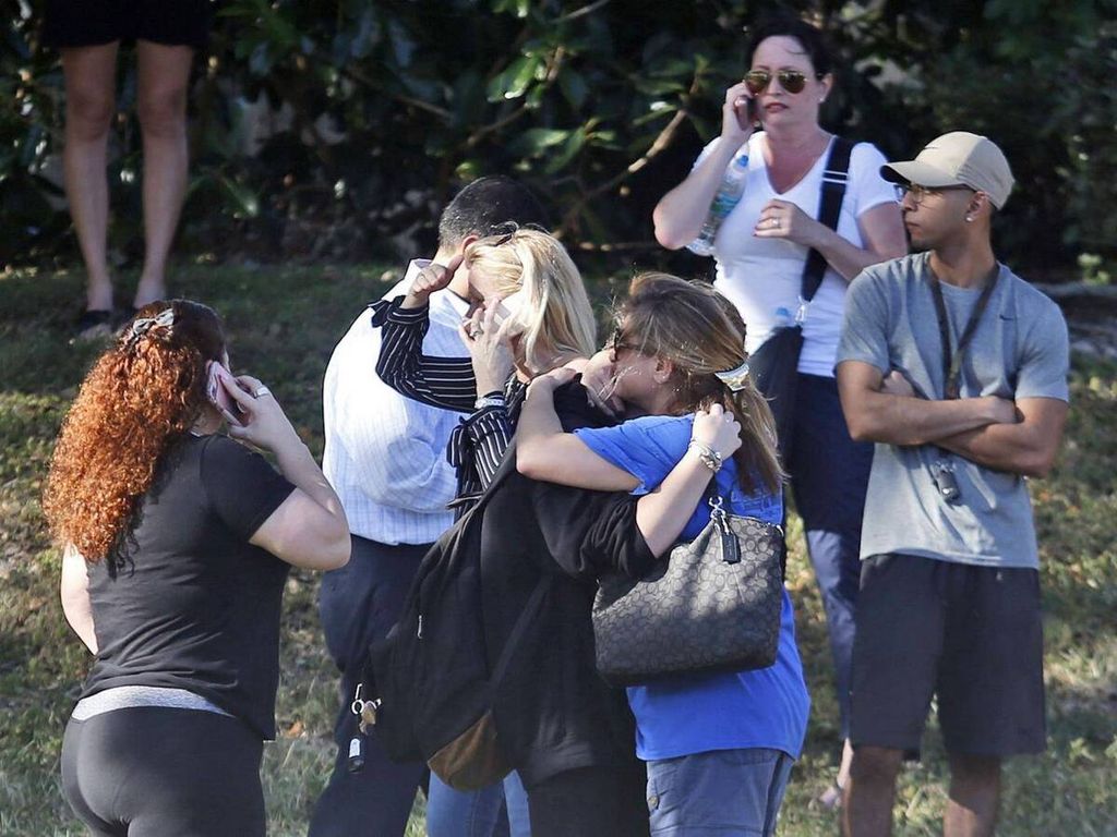 Para orangtua menanti dengan cemas dan saling berangkulan saat mendengar kabar penembakan di SMA Marjory Stoneman Douglas, Parkland, Florida, AS, Rabu (14/2/2018) waktu setempat.