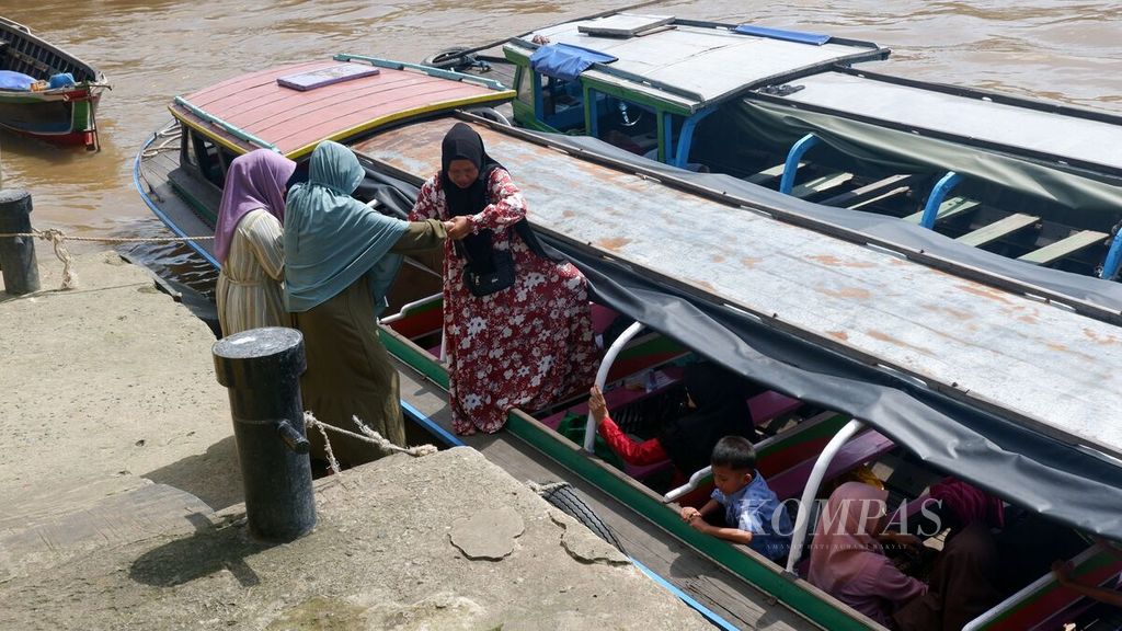 Warga membantu warga lainnya menaiki kapal tujuan Tamban Catur, Kabupaten Kapuas, Kalimantan Tengah, di Dermaga Pasar Baru, Kota Banjarmasin, Kalimantan Selatan, Senin (29/1/2024). 