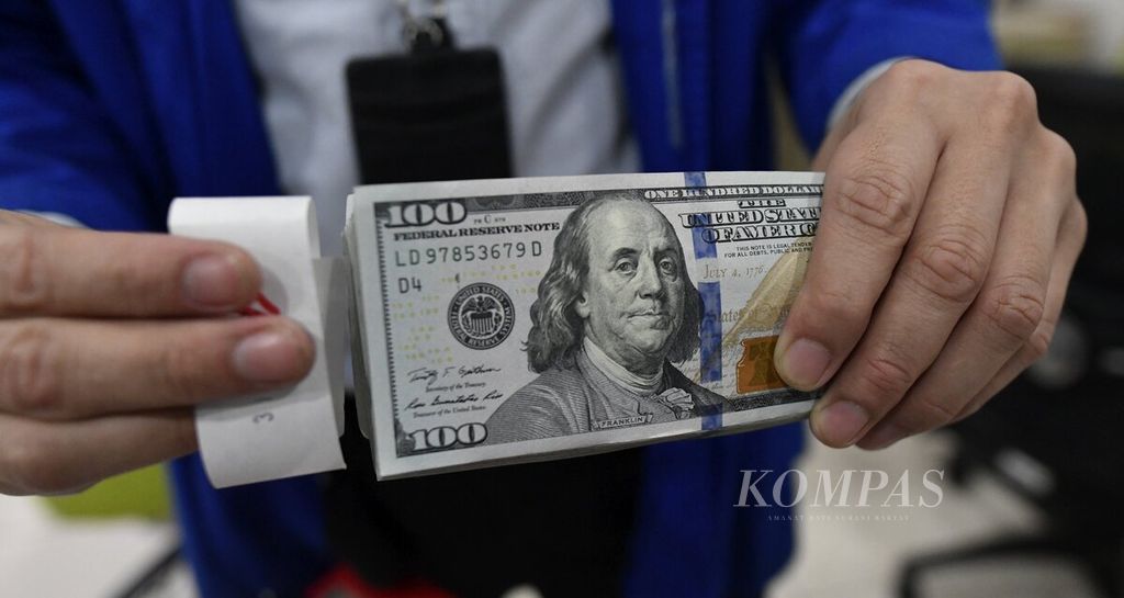 Petugas menunjukkan mata uang dollar AS di sentra kas Bank Mandiri, Jakarta, Selasa (5/4/2022).