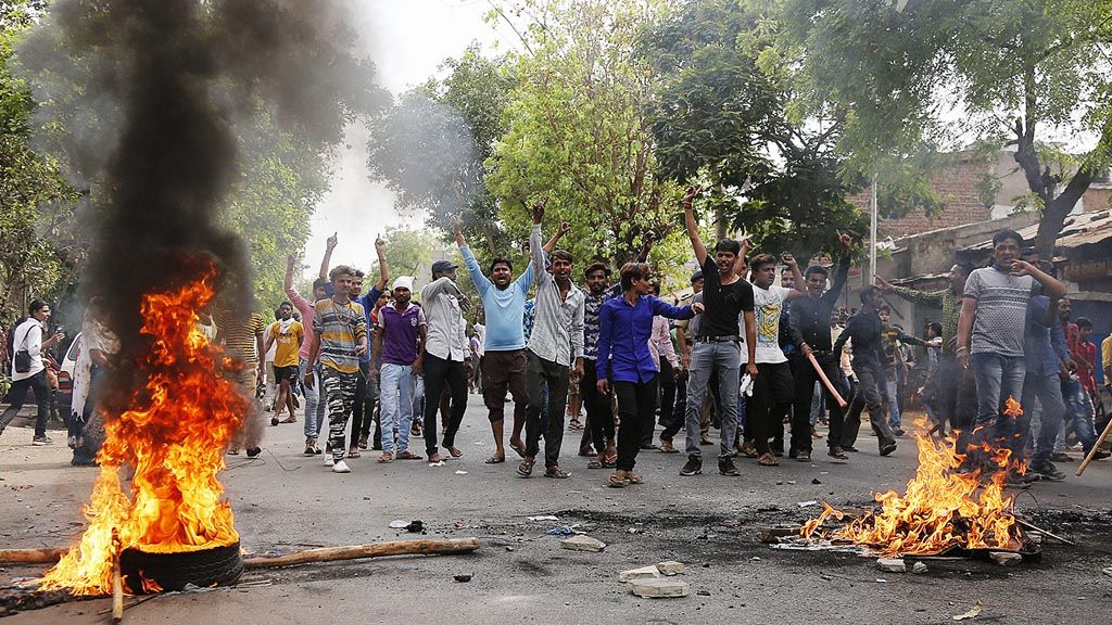 Warga  kasta terendah di India,  Dalit, berunjuk rasa sambil membakar ban dan memblokir arus lalu lintas selama pemogokan nasional di Ahmedabad, India, Senin (2/4/2018). Warga Dalit  memprotes perintah dari pengadilan tinggi negara  yang melemahkan upaya perlindungan hukum untuk komunitas mereka yang terpinggirkan. 