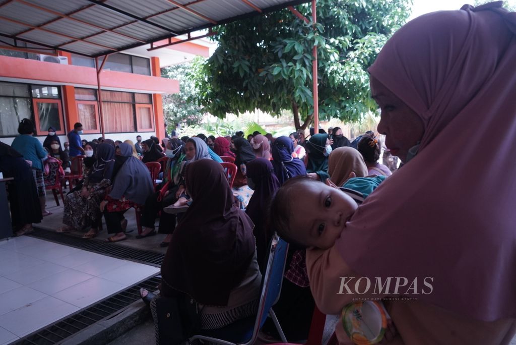 Sambil menggendong cucunya, Fatih (9 bulan), Ningsih (49) antre untuk menerima BLT minyak goreng di Kendari, Sulawesi Tenggara, Rabu (13/4/2022).