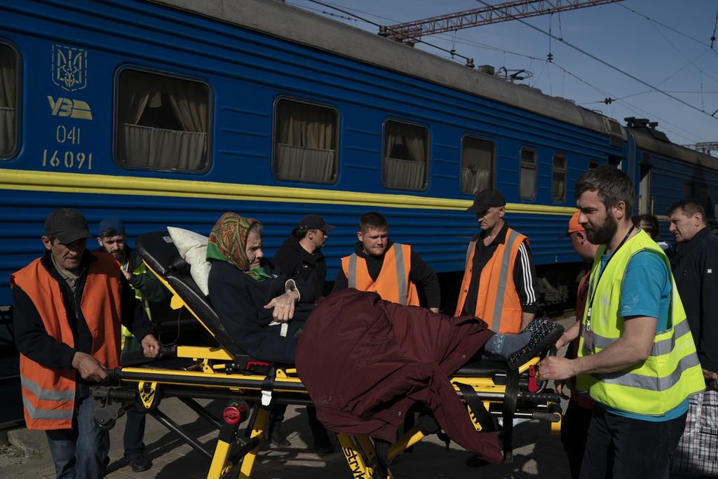 Seorang perempuan lanjut usia diangkut dengan tandu dorong sebelum dinaikkan ke kereta di stasiun kereta di Pokrovsk, Ukraina, Senin (25/4/2022). 