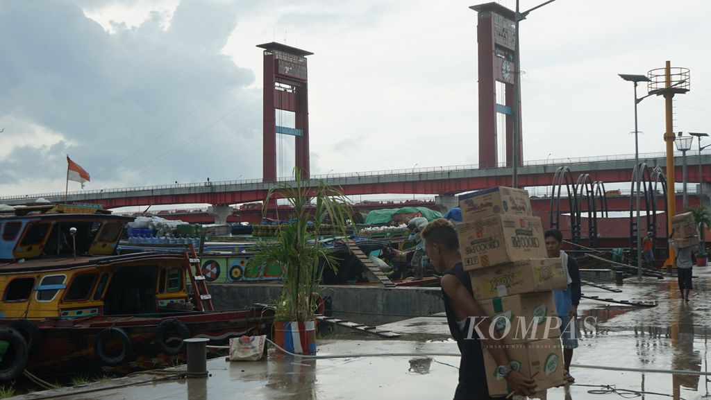 Aktivitas di dermaga 16 Ilir Palembang, Sumatera Selatan dengan latar belakang Jembatan Ampera dan kereta ringan (light rail transit/LRT), Selasa (20/12/2022). 