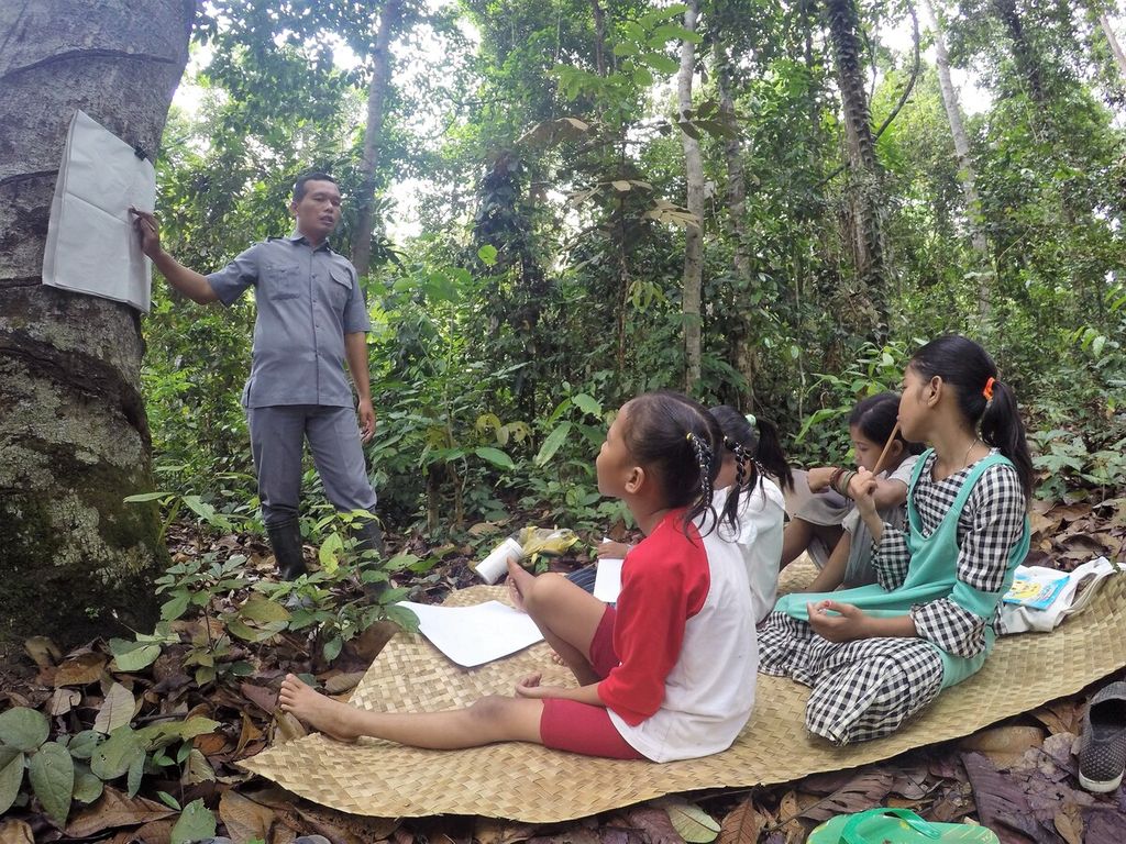 Teguh dan siswanya dari Suku Batin Sembilan di Hutan Harapan, dalam kegiatan belajar mengajar di wilayah Kelompang, Kabupaten Batanghari, Jambi, Jumat (26/11/2021). 