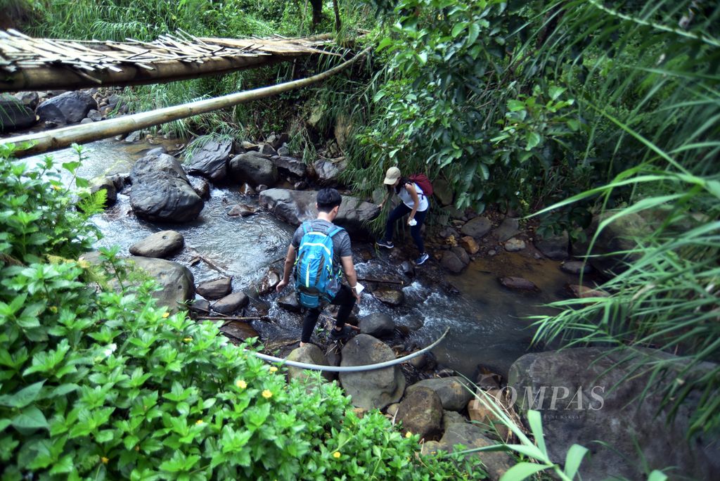 Pengunjung individu menyeberangi sungai di salah satu jalur <i>trekking </i>di kawasan Sentul, Kecamatan Babakan Madang, Kabupaten Bogor, Jawa Barat, Sabtu (19/11/2022). 