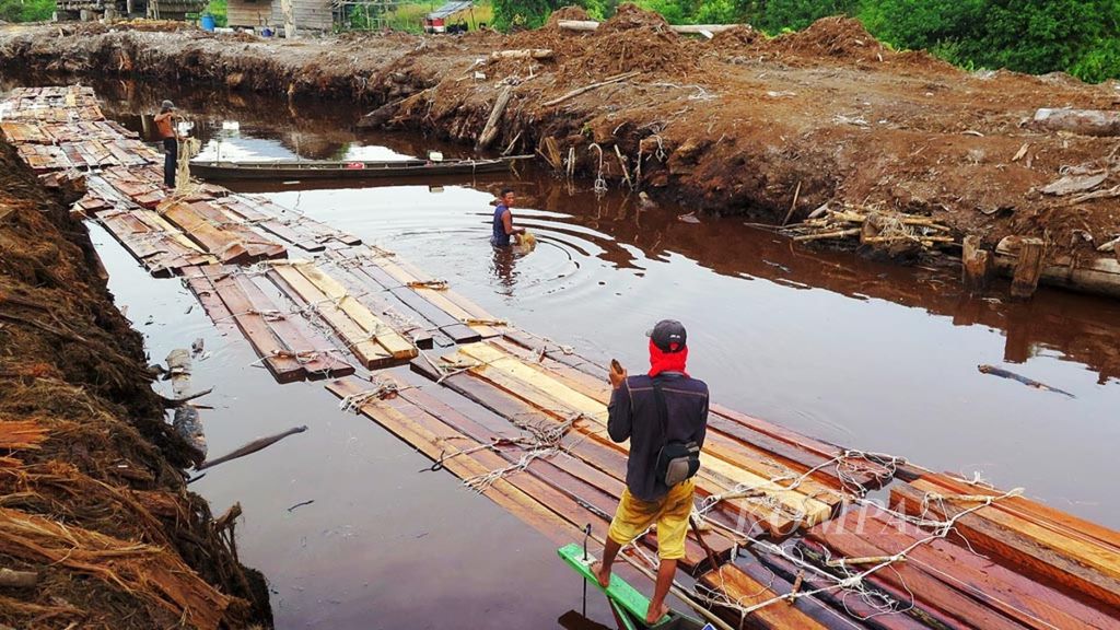 Pekerja angkut kayu melansir kayu-kayu curian lewat kanal PT Pesona Belantara Persada di Kecamatan Kumpeh, Kabupaten Muaro Jambi, Jambi, pertengahan Maret 2019. 