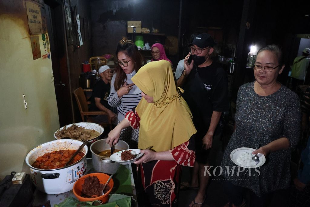 Penggemar kuliner membeli gudeg di warung Gudeg Pawon, Kecamatan Umbulharjo, Kota Yogyakarta, Senin (8/5/2023) malam. <i>Pawon</i> atau dapur tradisional yang digunakan sebagai tempat berdagang gudeg pada malam hari menjadi salah satu daya tarik warung ini.