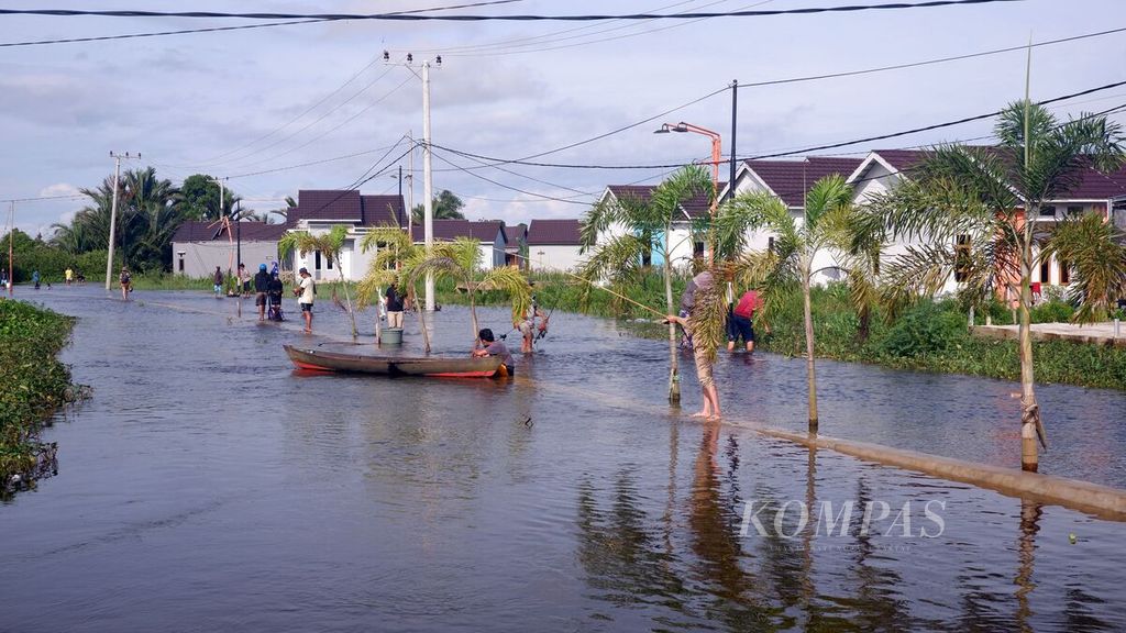 Beberapa warga memancing di sungai yang meluap di dekat kompleks perumahan di Kelurahan Sungai Lulut, Kecamatan Banjarmasin Timur, Kota Banjarmasin, Kalimantan Selatan, Sabtu (16/1/2021). 