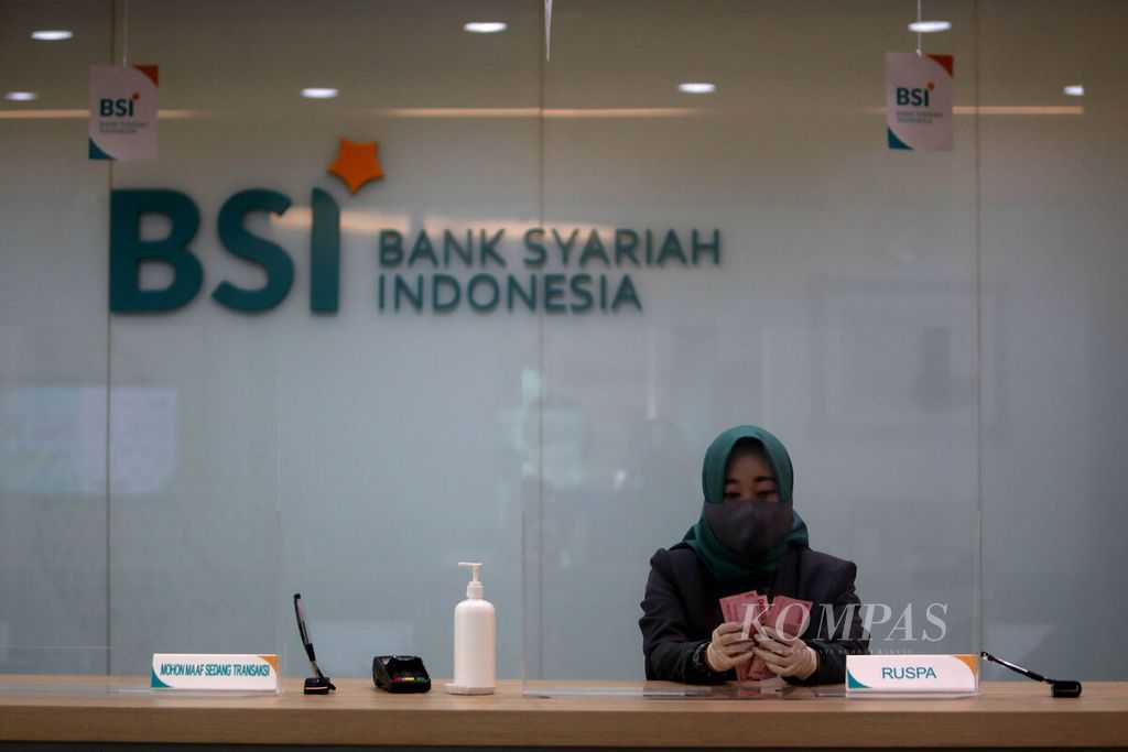 <i>Teller </i>Bank Syariah Indonesia menghitung uang rupiah di Kantor Cabang Hasanudin, Blok M, Jakarta (1/2/2021). Bank yang merupakan hasil merger dari PT Bank BRI Syariah Tbk, PT Bank BNI Syariah, dan PT Bank Syariah Mandiri tersebut resmi beroperasi pada 1 Februari 2021. 