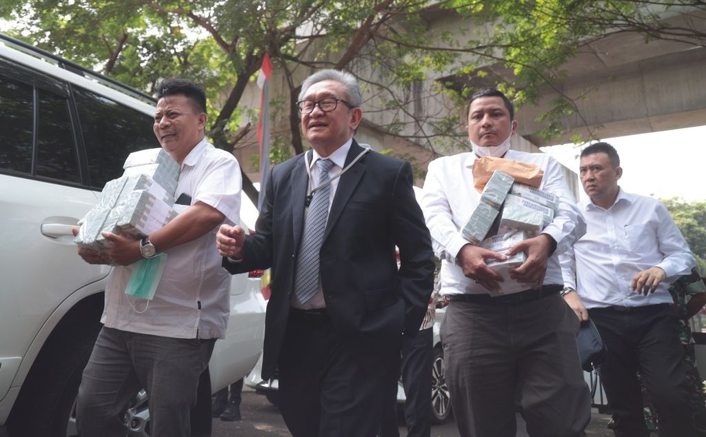 Kuasa hukum terdakwa kasus dugaan korupsi pengadaan<i> base transceiver station</i> (BTS) Bakti Kementerian Komunikasi dan Informatika (Kominfo) 2020-2022 Irwan Hermawan, Maqdir Ismail (berjas), membawa uang Rp 27 miliar ke Kejaksaan Agung (Kejagung), Jakarta, Kamis (13/7/2023). Maqdir memenuhi panggilan Kejaksaan Agung untuk dimintai keterangan dan klarifikasi lebih lanjut terkait informasi soal pengembalian uang Rp 27 miliar dalam kasus dugaan korupsi pengadaan BTS Bakti Kominfo. Maqdir membawa tumpukan uang pecahan dollar AS senilai 1,8 juta. 