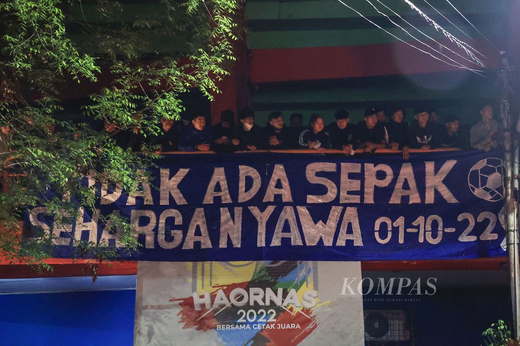 Spanduk kecaman dipasang Aremania saat melakukan doa bersama di luar Stadion Gajayana, Malang, Jawa Timur, Minggu (2/10/2022). Mereka menyalakan lilin dan berdoa bersama untuk korban tragedi Kanjuruhan yang merenggut 125 nyawa Aremania. 