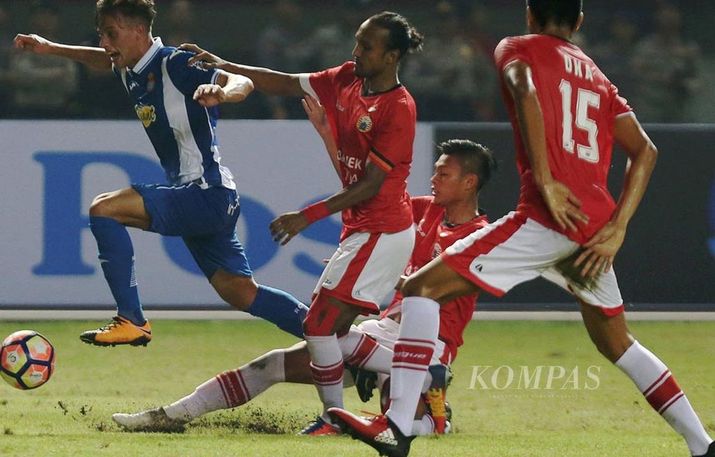 Pemain RCD Espanyol Leonardo Carrilho Baptista (biru) ditempel ketat pemain Persija Jakarta dalam laga persahabatan di Stadion Patriot Candrabhaga, Bekasi, Jawa Barat, Rabu (19/7). RCD Espanyol menundukkan Persija Jakarta 7-0.  
