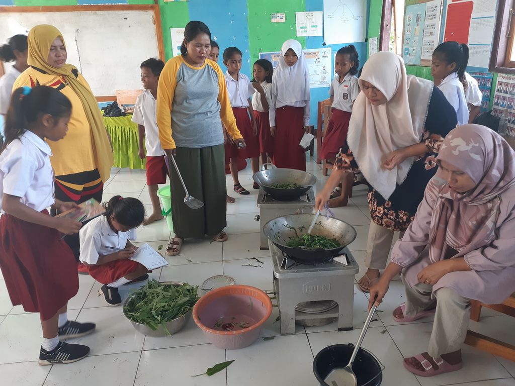 Siswa kelas V SD Negeri Waikelo di Kabupaten Sumba Barat Daya, Nusa Tenggara Timur, mengamati sejumlah orangtua yang memasak kangkung hasil panen dari kebun pangan di sekolah, Selasa (31/5/2022). Para siswa belajar literasi dengan menuliskan resep masakan secara kontekstual dari pengolahan sayur kangkung di sekolah. 