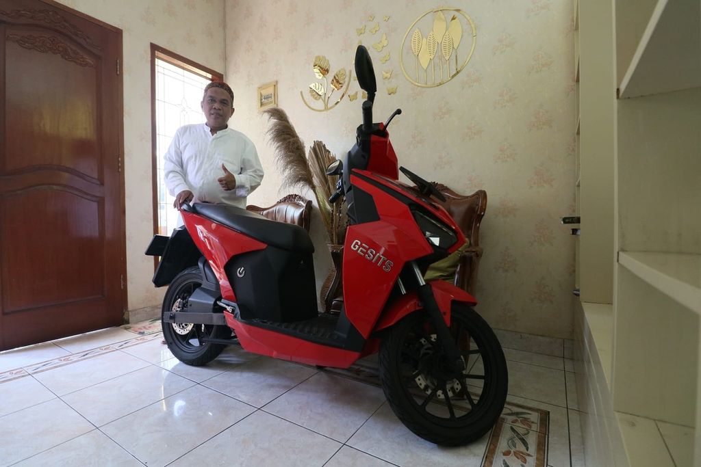Salah seorang warga Palmerah, Jakarta Barat Sofian berfoto di samping motor listrik Gesits pada Sabtu (24/09/2022). Motor yang dibelinya tahun 2020 lalu biasa Sofian gunakan untuk mobilitas jarak dekat seperti masjid maupun pasar.