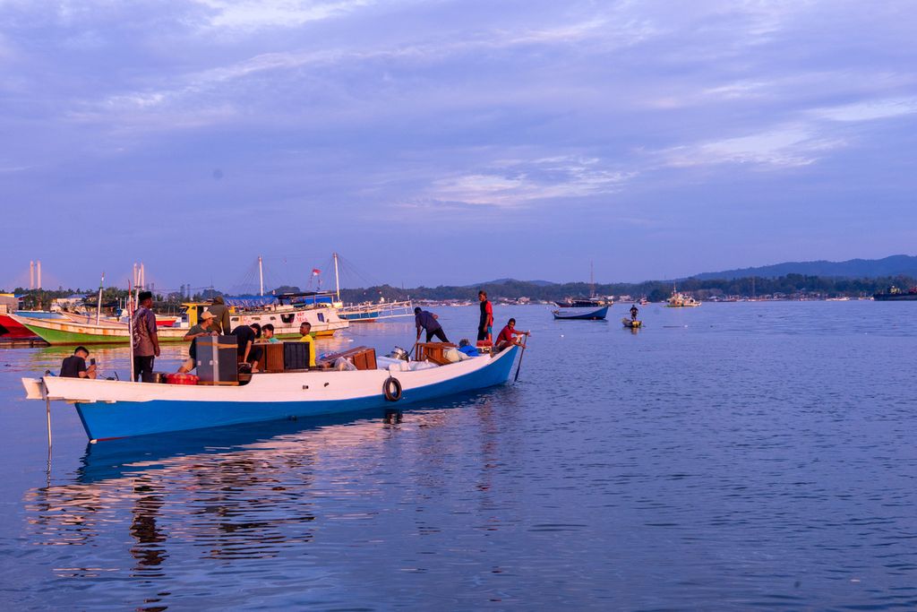 Sejumlah warga yang juga nelayan membawa barang untuk dipindahkan ke kapal di Teluk Kendari, Sulawesi Tenggara (28/3/2022). Nelayan kecil di wilayah ini menghadapi berbagai tantangan, utamanya dengan konflik jalur penangkapan yang telah diatur pemerintah.