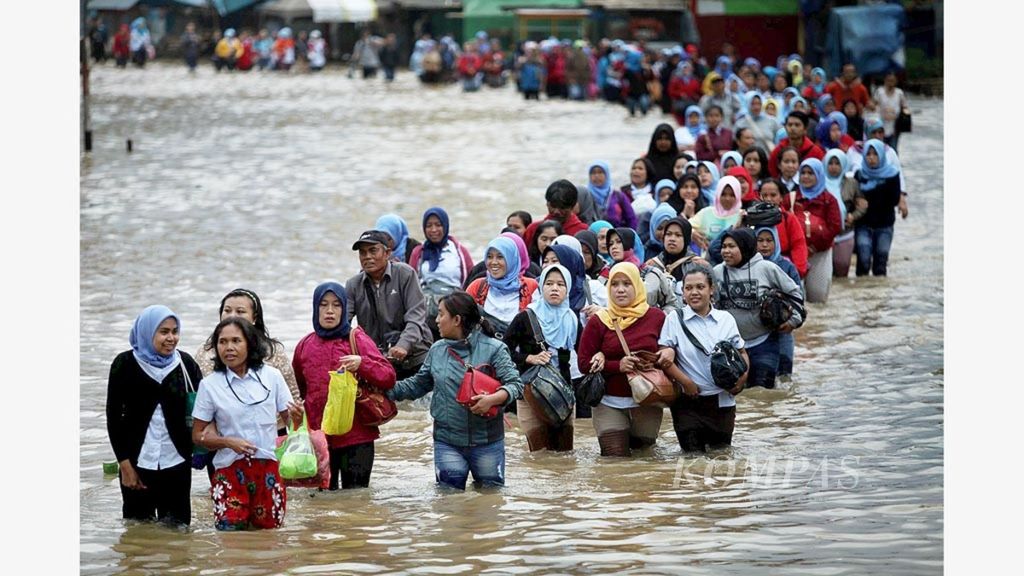 Buruh pabrik berjalan beriringan saat pulang kerja melintasi Jalan Raya Dayeuhkolot, Kabupaten Bandung, Jawa Barat, yang terendam banjir, Rabu (8/3/2017).