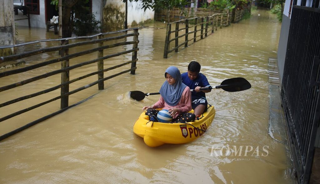 Anek menaiki kano saat banjir di Desa Blega, Kecamatan Blega, Kabupaten Bangkalan, Jawa Timur, Minggu (1/1/2023). Banjir mulai terjadi pada Sabtu (31/12/2022) siang dan membesar hingga Minggu dini hari. 