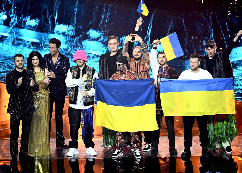 Anggota "Kalush Orchestra" (kanan) merayakan kemenangannya di atas panggung dengan mengibarkan bendera Ukraina. Band yang mewakili Ukraina itu memenangi kontes Eurovision Song 2022 pada 14 Mei 2022 di Pala Alpitour di Turin, Italia. (Photo by Marco BERTORELLO / AFP)