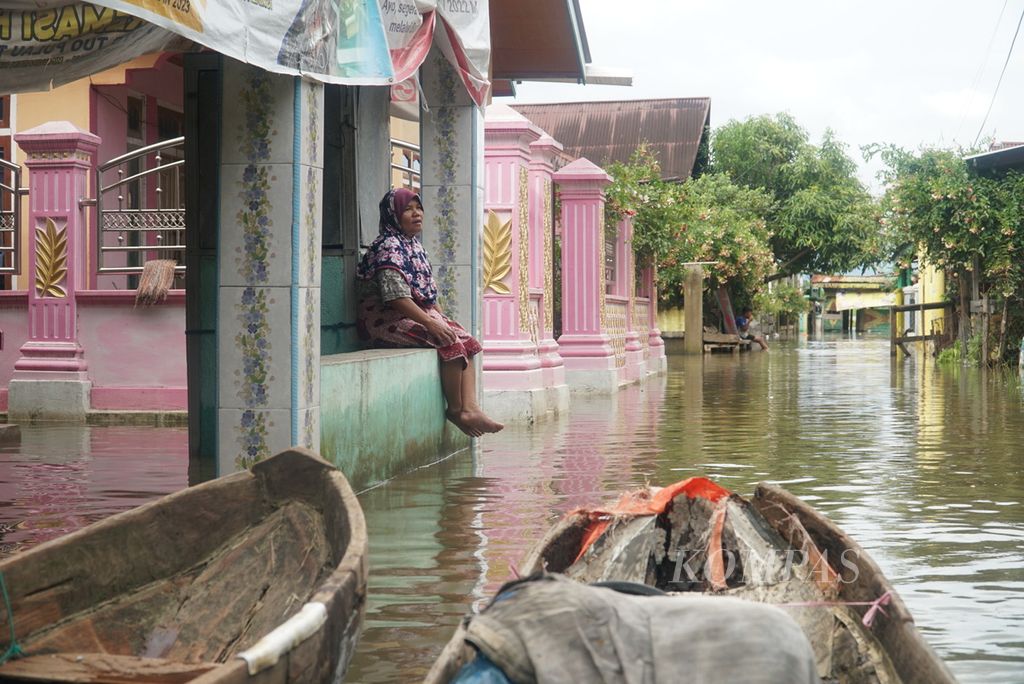 Warga sedang duduk di depan rumahnya yang terendam banjir akibat meluapnya Danau Kerinci di Desa Pulau Tengah, Kecamatan Keliling Danau, Kabupaten Kerinci, Jambi, Selasa (16/1/2024). 