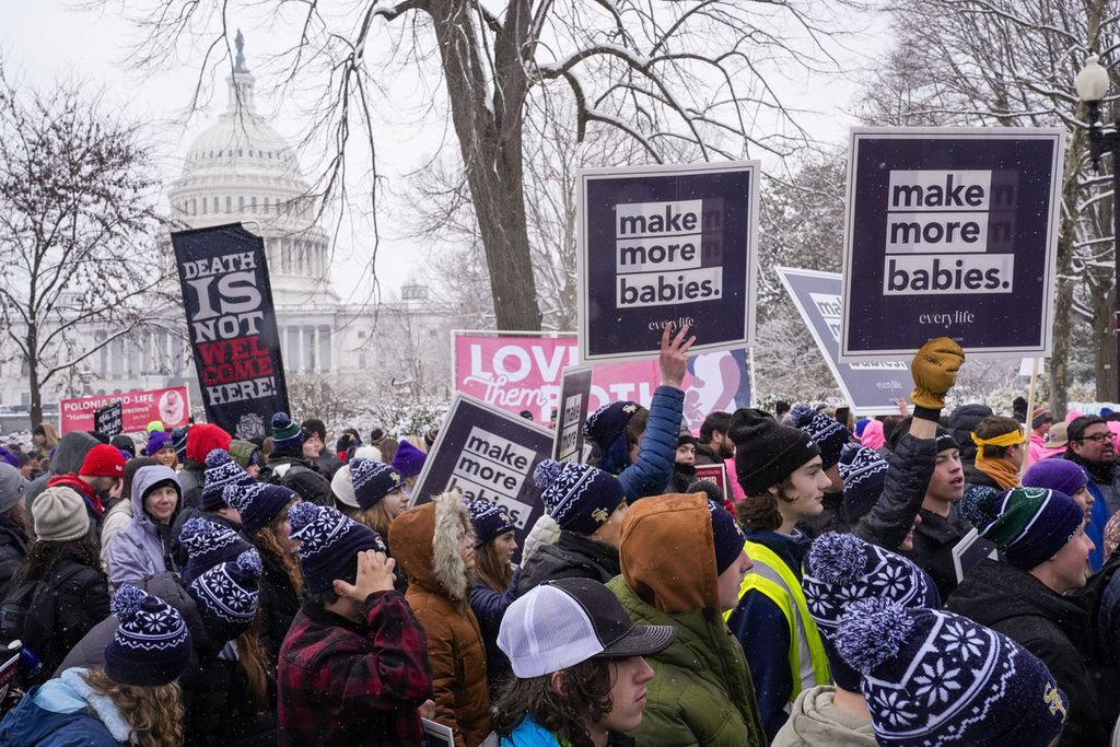 Kaum muda memegang plakat bertuliskan "hasilkan lebih banyak bayi" saat mereka berjalan dari Gedung Capitol dan Mahkamah Agung, saat unjuk rasa March for Life, Jumat (19/1/2024) di Washington.