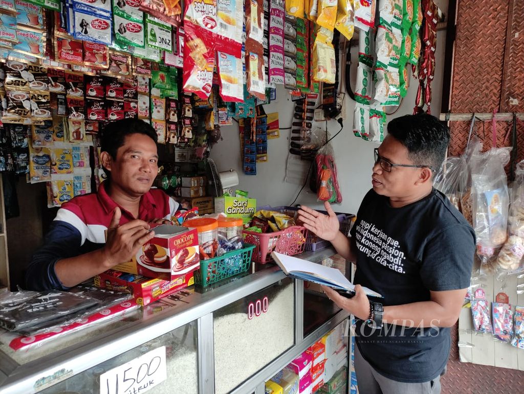 Penjaga warung, Holis (48), berbincang dengan pemilik usaha tersebut, Abdul Hamied (44), di Depok, Jawa Barat, Selasa (7/2/2023).