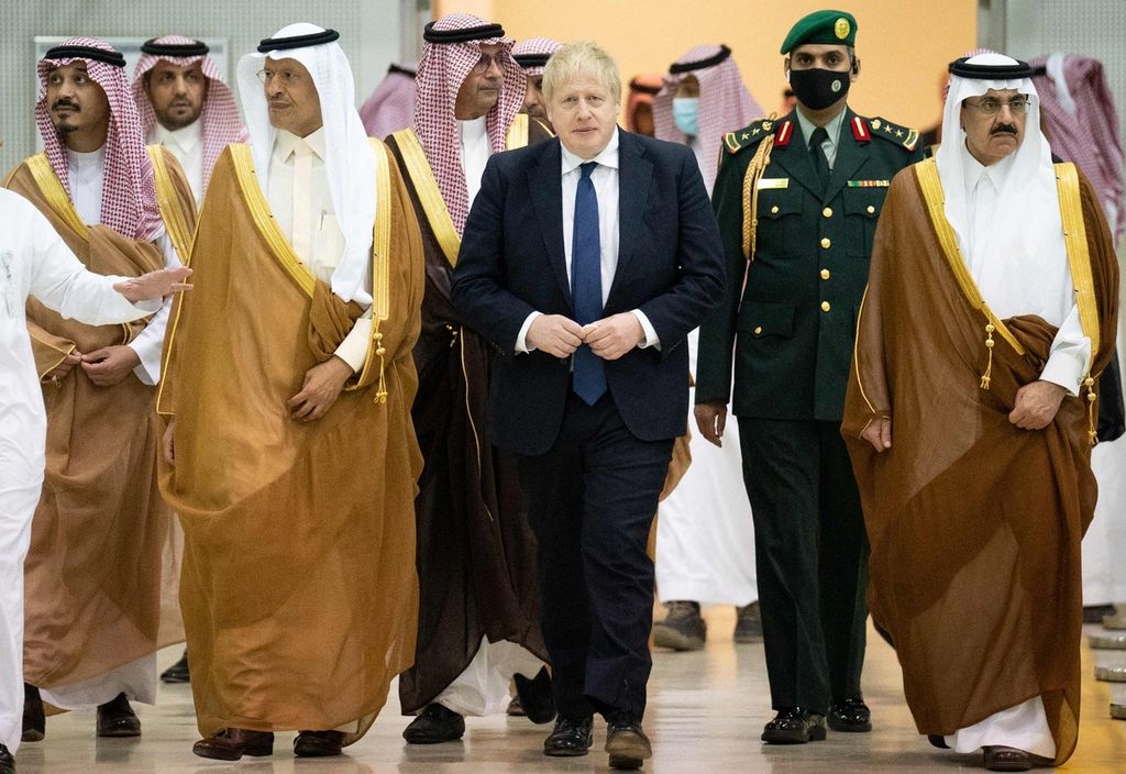 Perdana Menteri Inggris Boris Johnson (tengah) berjalan bersama Menteri Energi Arab Saudi Abdulaziz bin Salman (kedua dari kiri) dan para pejabat lainnya di kantor pusat Saudi Basic Industries (SABIC), Riyadh, Arab Saudi, 16 Maret 2022.