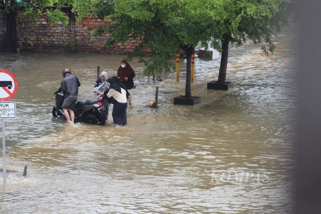 Seorang pengendara motor sedang mendorong kendaraannya kala banjir merendam ruas Jalan Basuki Rahmat, Palembang, Sumatera Selatan, Sabtu (25/12/2021). Banjir ini disebabkan oleh meningkatnya curah hujan dan meluapnya anak Sungai Musi.