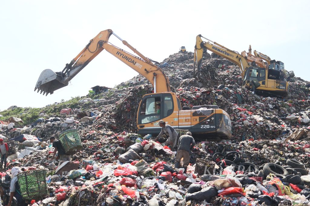 Pemulung mengais sampah dan petugas merapikan sampah dengan alat berat di TPA Bantar Gebang pada Selasa (26/04/2022).