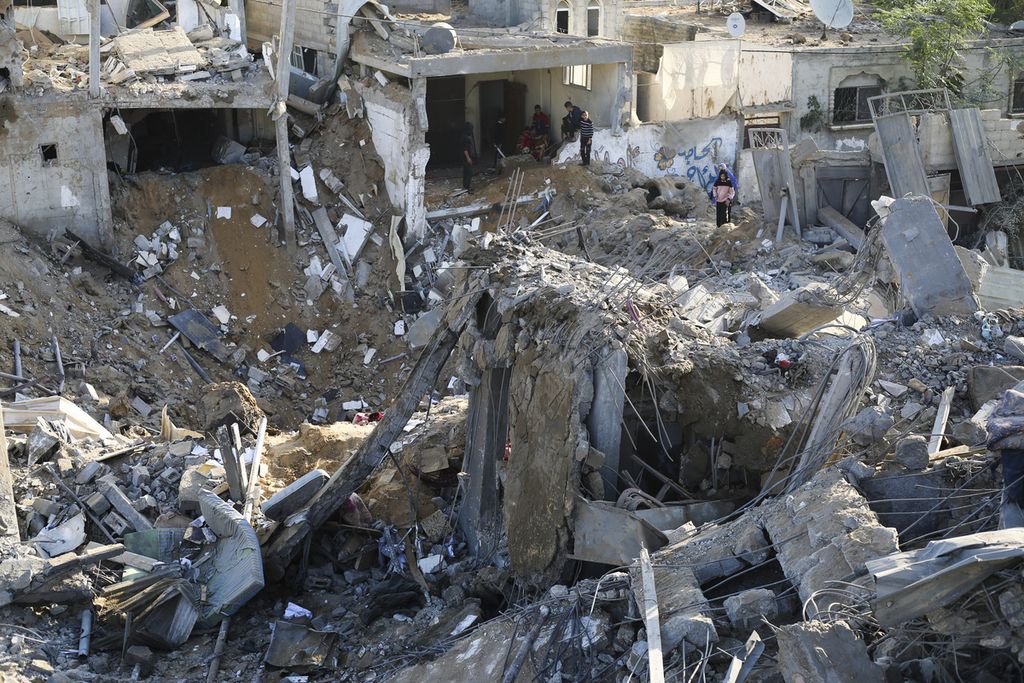 Warga Palestina melintas di sebuah lokasi bangunan yang hancur lebur setelah serangan Israel di Rafah, Gaza selatan, Sabtu (4/12/2023). 