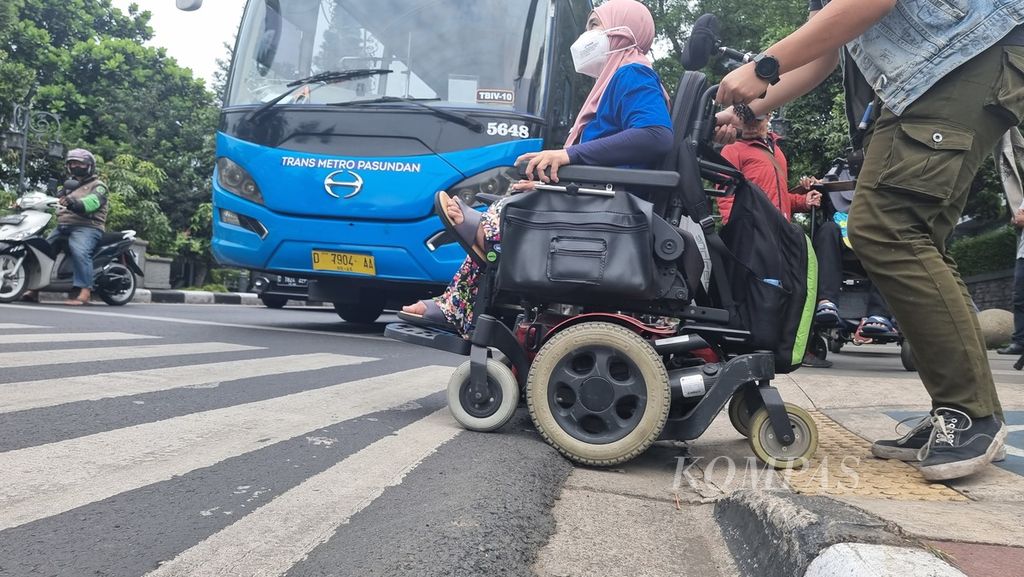 Pengguna kursi roda kesulitan melintasi jalan khusus penyandang disabilitas saat menyeberang perempatan Dago-Cikapayang, Kota Bandung, Jawa Barat, Selasa (1/3/2022).