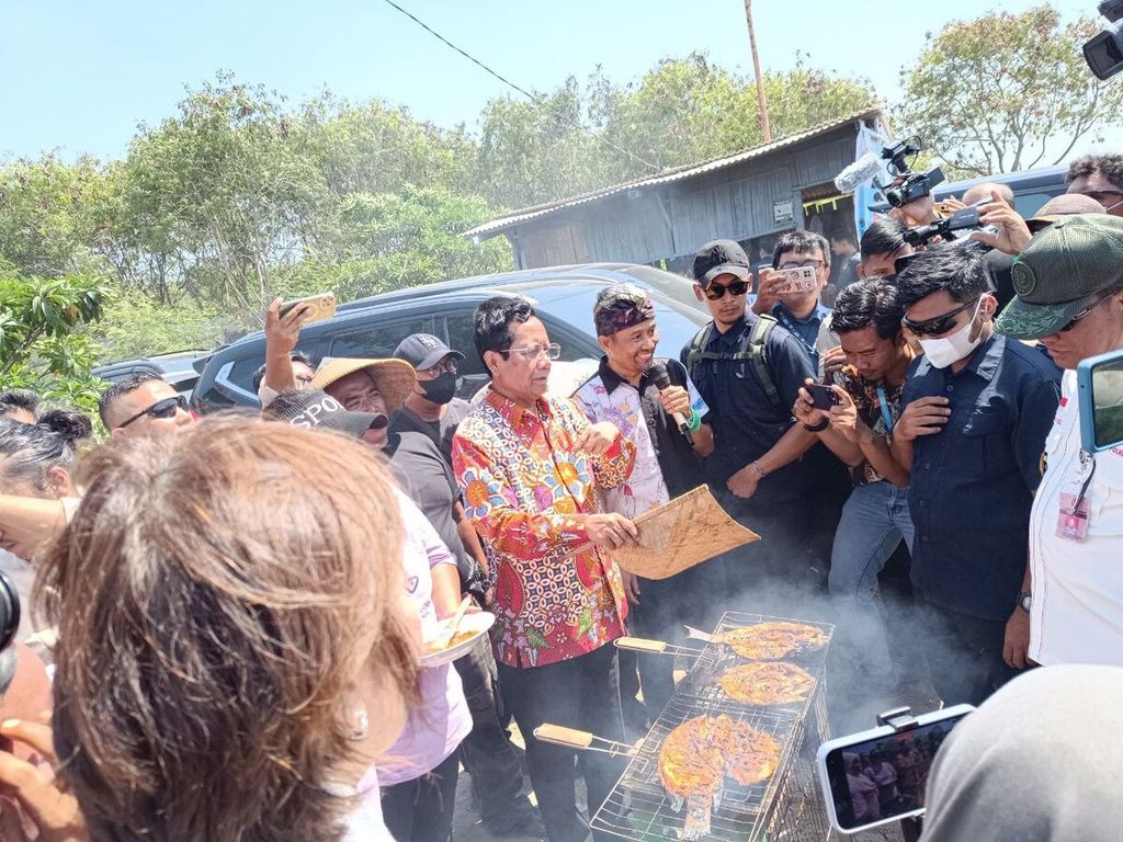 Menteri Koordinator Bidang Politik, Hukum, dan Keamanan Mahfud MD membakar ikan di kampung nelayan Marunda, Cilincing, Jakarta Utara, Rabu (20/12/2023).