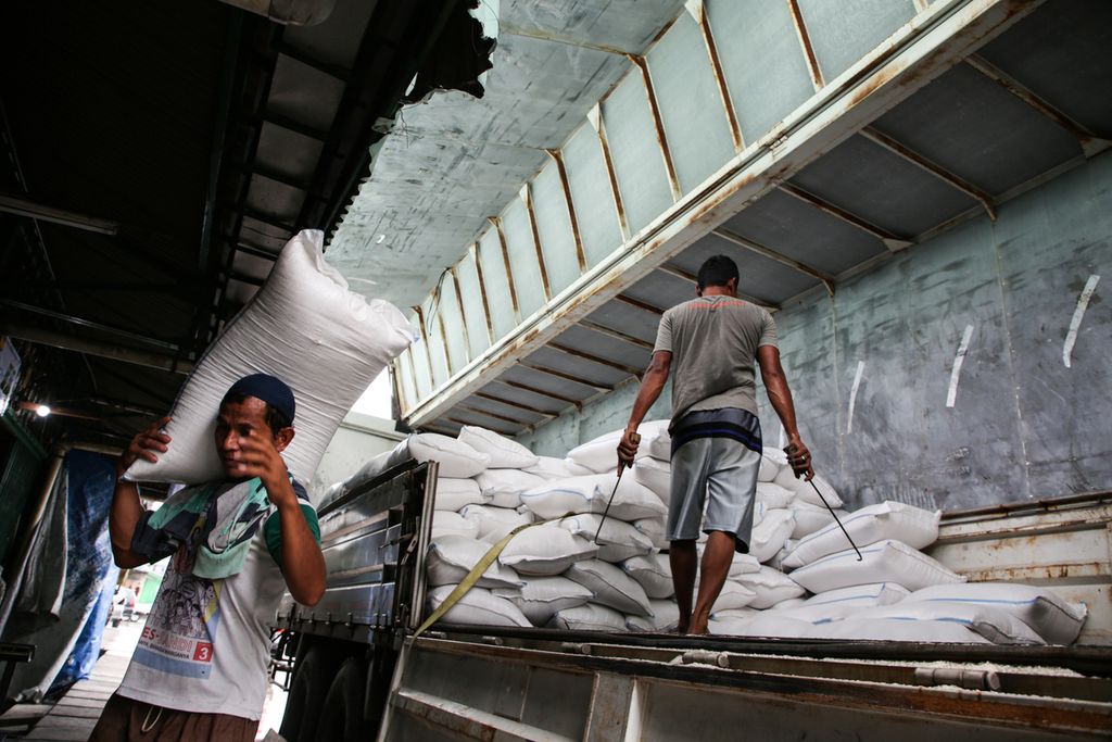 Pekerja menurunkan beras asal Demak, Jawa Tengah, di Pasar Induk Beras Cipinang, Jakarta Timur, Minggu (5/3/2023).