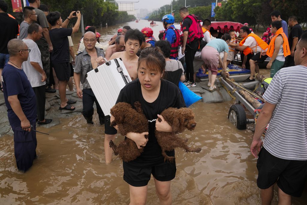 Seorang perempuan membawa dua anjing peliharannya setelah berhasil diselamatkan regu penyelamat sesudah tempat tinggalnya dilanda banjir di Zhuozhou, Provinsi Hebei, China, Rabu (2/8/2023). 