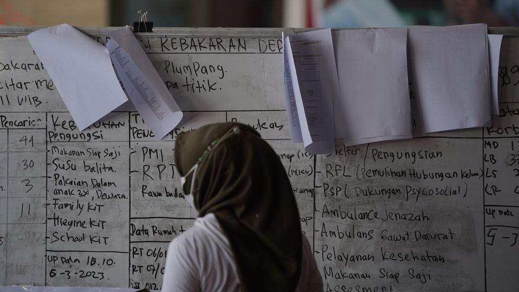 Warga melintasi papan barang kebutuhan dan pelayanan yang dibutuhkan pengungsi korban kebakaran Terminal Integrated Bahan Bakar Minyak (BBM) Depo Pertamina Plumpang di Posko PMI, Jakarta Utara, Senin (6/3/2023). 