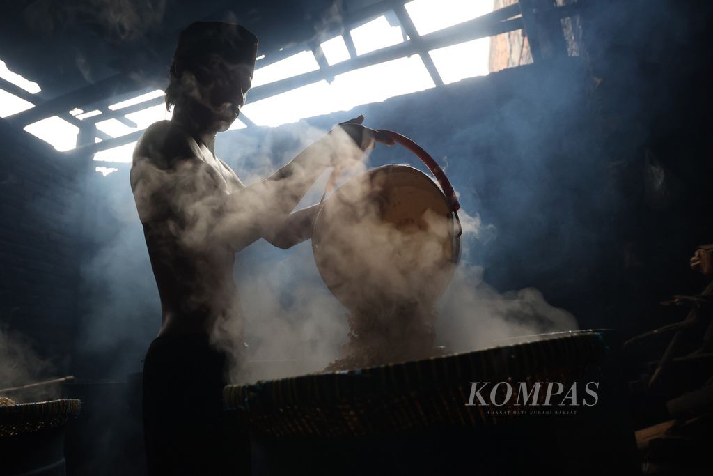 Pekerja menuang kedelai yang telah direbus untuk diolah menjadi tempe di Desa Sinduadi, Mlati, Sleman, DI Yogyakarta, Jumat (18/2/2022). 
