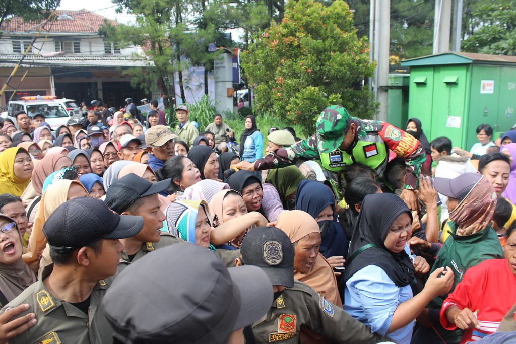 Petugas tampak kewalahan dan terdesak oleh kerumunan warga dalam Operasi Pasar Beras Stabilitas Pasokan Harga Pangan atau SPHP di Kecamatan Buahbatu, Kota Bandung, Jawa Barat, Senin (19/2/2024).