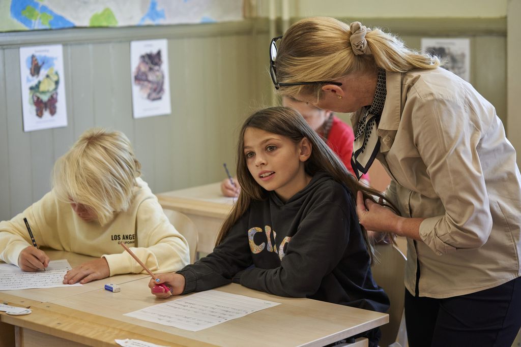 Seorang guru (kanan) membantu siswa-siswanya menulis dengan tangan di Sekolah Dasar Djurgardsskolan, di Stockholm, Swedia, Kamis (31/8/2023).  