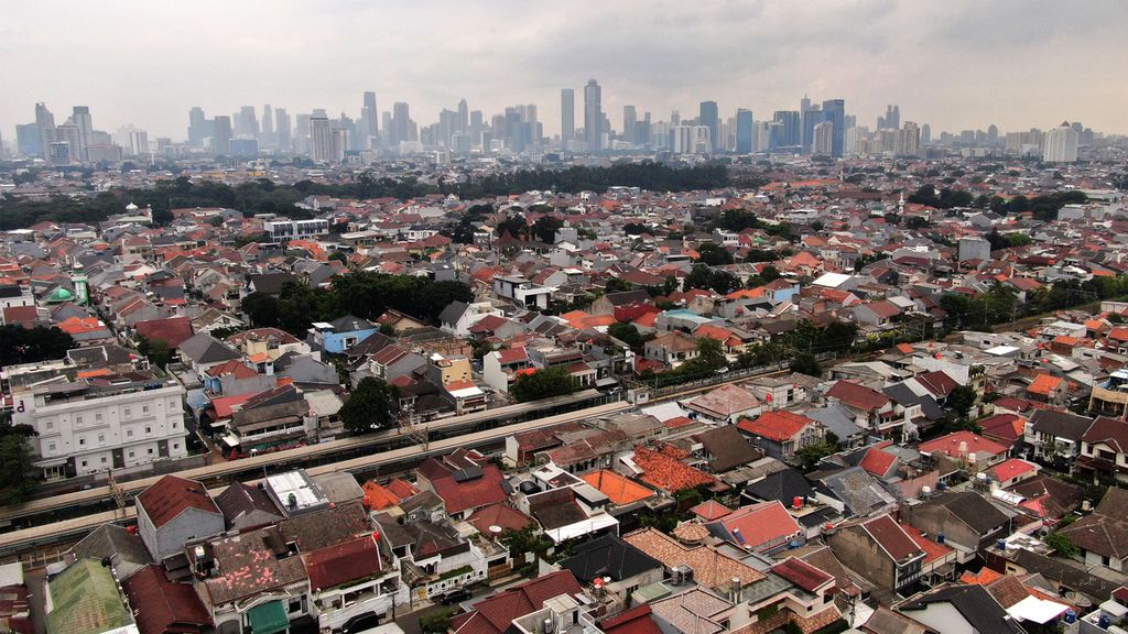 Kawasan permukiman padat penduduk dengan latar belakang gedung bertingkat di Jakarta, Rabu (18/1/2023).