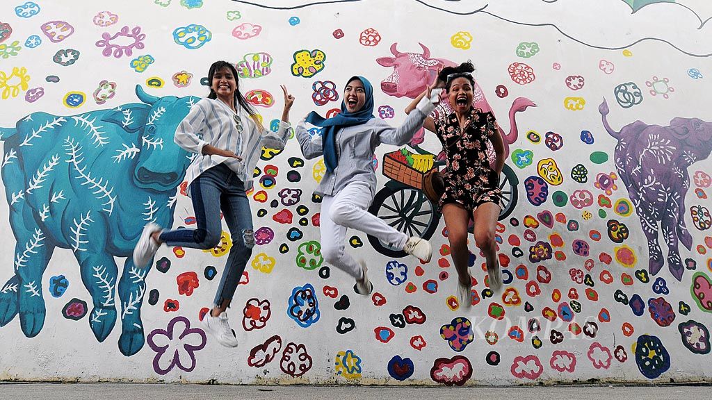anak-anak muda Singapura berpose dengan latar belakang mural yang terpampang di salah satu bangunan di Little India Singapura, Jumat (26/1). 
