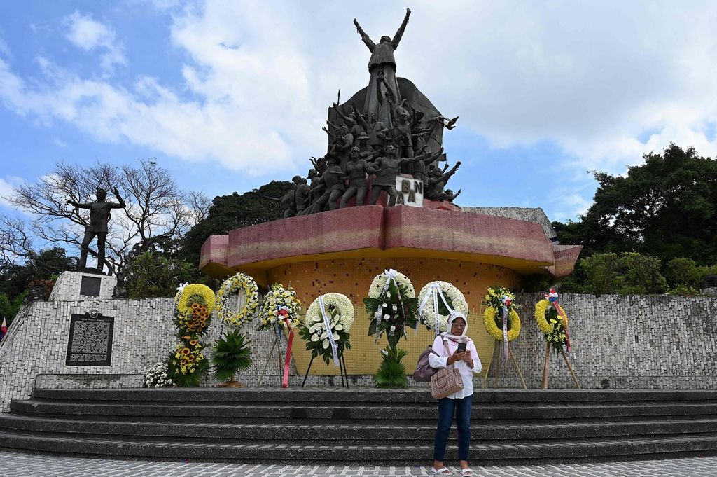Seorang perempuan berdiri di depan Monumen People Power di Epifanio de los Santos Avenue atau EDSA, Quezon City, Filipina, 25 Februari 2023, dalam unjuk rasa memperingati 37 tahun revolusi People Power yang menggulingkan Presiden Filipina Ferdinand Marcos senior. 