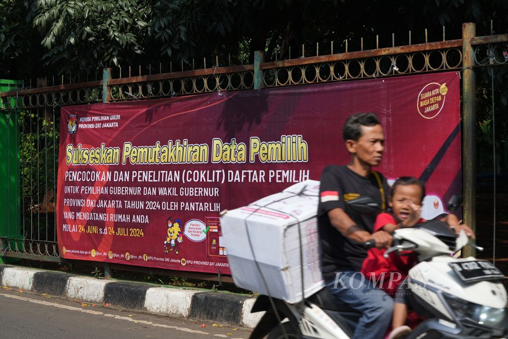 Warga melintas di dekat bentangan spanduk ”Sukseskan Pemutakhiran Data Pemilih” di Cakung, Jakarta Timur, Selasa (9/7/2024). 