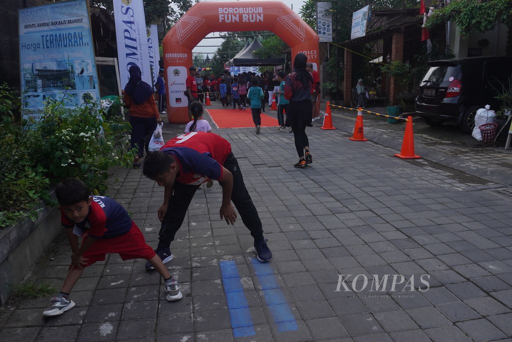Ayah dan anak peserta Borobudur Fun Run melakukan gerakan pendinginan seusai finis di kawasan Candi Pawon, Kecamatan Borobudur, Kabupaten Magelang, Jawa Tengah, Sabtu (3/12/2023). 