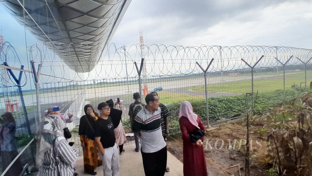 Warga yang penasaran ingin melihat <i>runway</i> di Bandar Udara Dhoho, Kediri, Jawa Timur, mencoba melongok melalui pagar dari sisi samping terminal, Minggu (10/3/2024).
