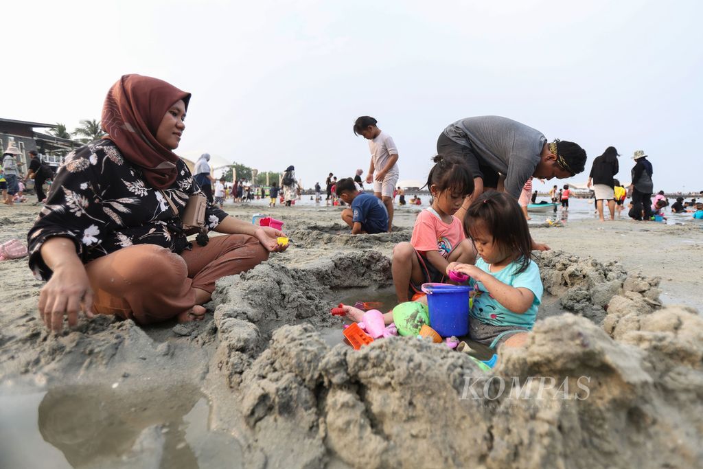 Seorang ibu menjaga anaknya saat bermain pasir di Pantai Ancol, Jakarta, Senin (25/12/2023). Ancol Taman Impian masih menjadi salah satu tujuan wisata favorit warga saat Libur Natal 2023 dan Tahun Baru 2024. Hingga sore, Ancol dikunjungi 55.000 orang. 