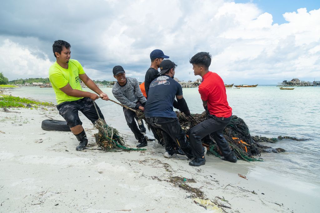 Sukarelawan dari Seven Clean Seas mengangkat sampah jaring di pesisir Desa Pengudang, Kecamatan Teluk Sebong, Kabupaten Bintan, Kepulauan Riau, Rabu (20/10/2021).
