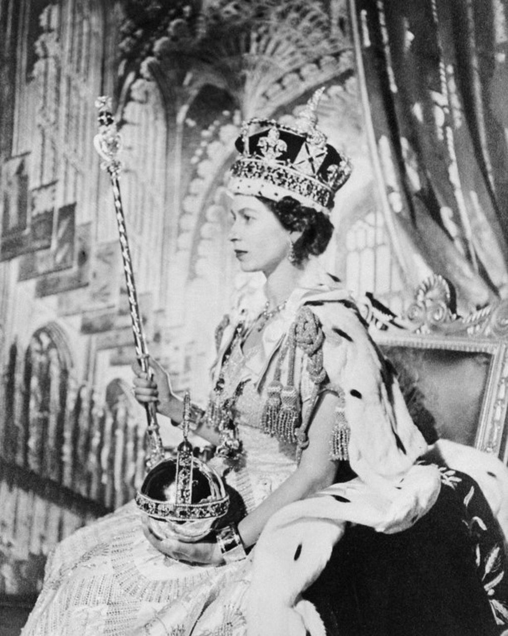 Ratu Elizabeth II dari Inggris Raya berpose pada hari penobatannya, pada 2 Juni 1953 di London. Di kepala terpasang mahkota, di tangan kanan tongkat kekuasaan, dan di tangan kiri bola salib emas (Orb), simbol dunia Kekristenan, kekuasaan, dan kedaulatan Ratu.