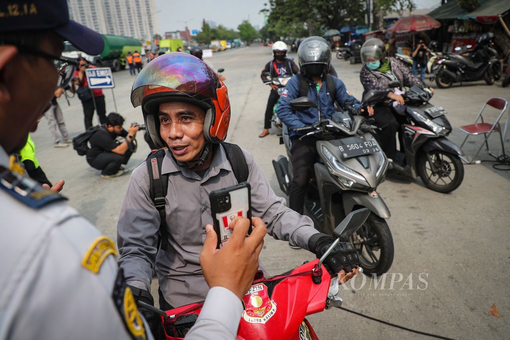 Petugas memberi penjelasan tentang uji emisi kendaraan kepada pengendara sepeda motor di Jalan Perintis Kemerdekaan, Jakarta Timur, Rabu (1/11/2023).